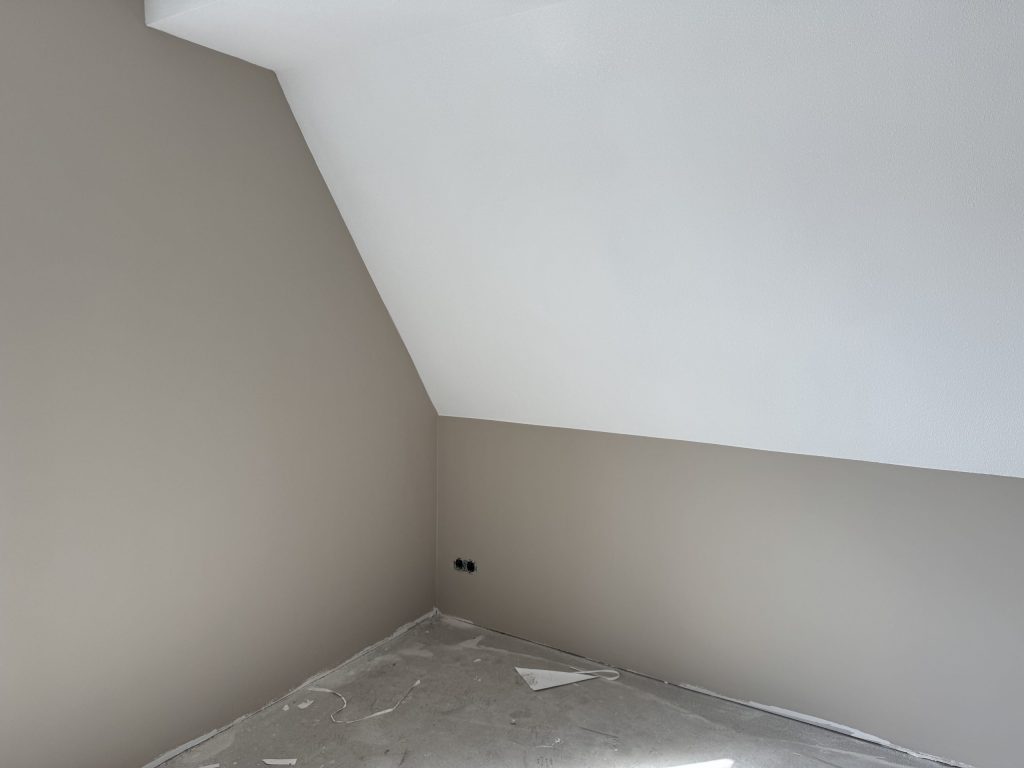 Zolderkamer in een nieuwbouwhuis met een schuine wand en egaal afgewerkte muren
